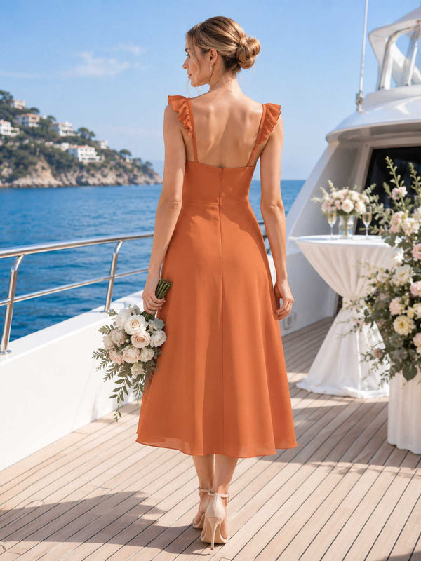 Back view of a burnt orange chiffon midi bridesmaid dress with open back, ruffle shoulder straps, back zipper, fitted bodice, and flowing A-line midi skirt.