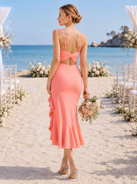 Back view of a coral chiffon midi bridesmaid dress with spaghetti straps, bow open back detail, center back zipper, cascading side ruffle, and flounced midi hem.