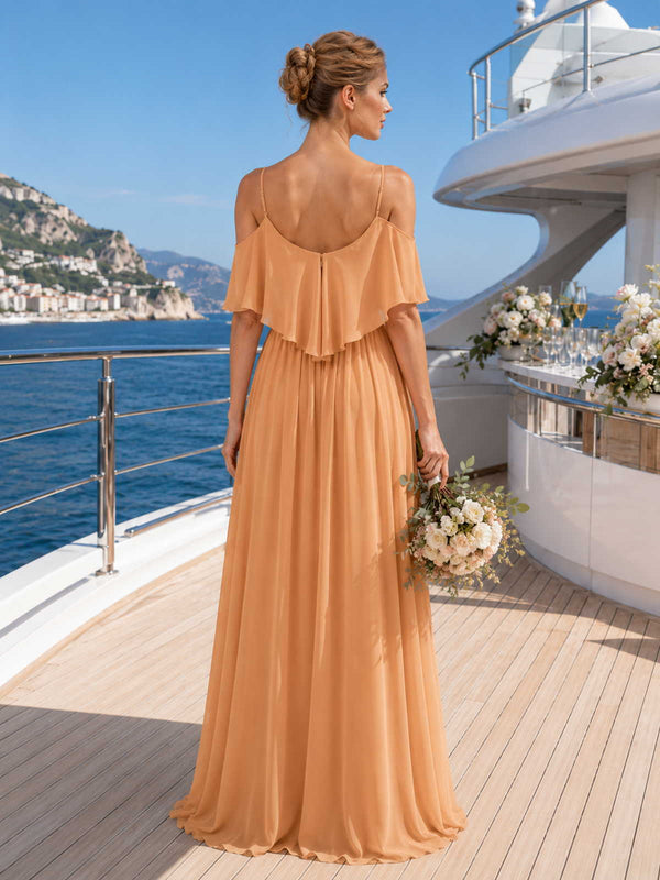 Back view of a soft peach chiffon floor-length bridesmaid dress with scoop back, spaghetti straps, cold shoulder ruffle overlay, center back zipper, gathered waist, and flowing A-line skirt.