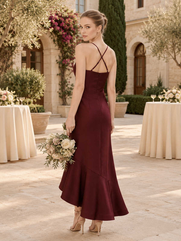 Back view of a burgundy satin midi bridesmaid dress with slim spaghetti straps, crisscross back detail, fitted silhouette, and softly flared asymmetrical mermaid hem.