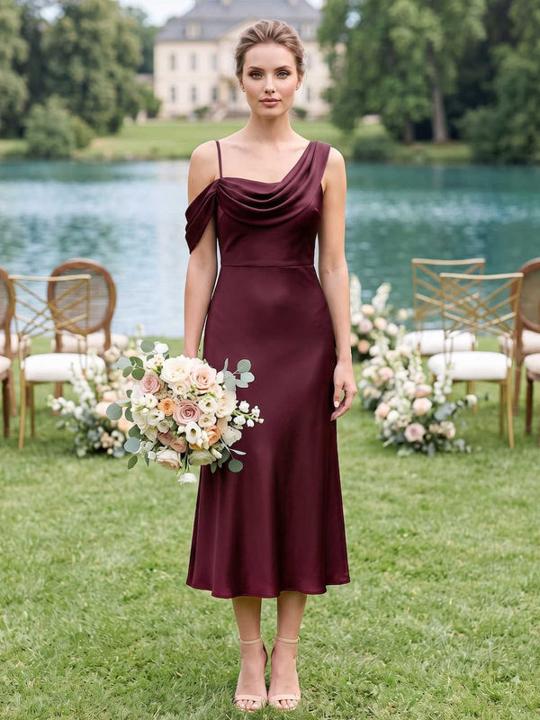 Front view of a burgundy satin midi bridesmaid dress with an asymmetrical one-shoulder neckline, softly draped bodice, slim strap detail, fitted waist, and flowing A-line skirt.