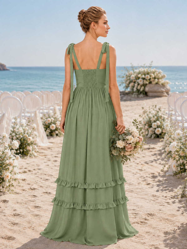 Back view of a sage green chiffon floor-length bridesmaid dress with self-tie shoulder straps, square open back, smocked back bodice, fitted waist, softly gathered A-line skirt, and tiered ruffle hem.