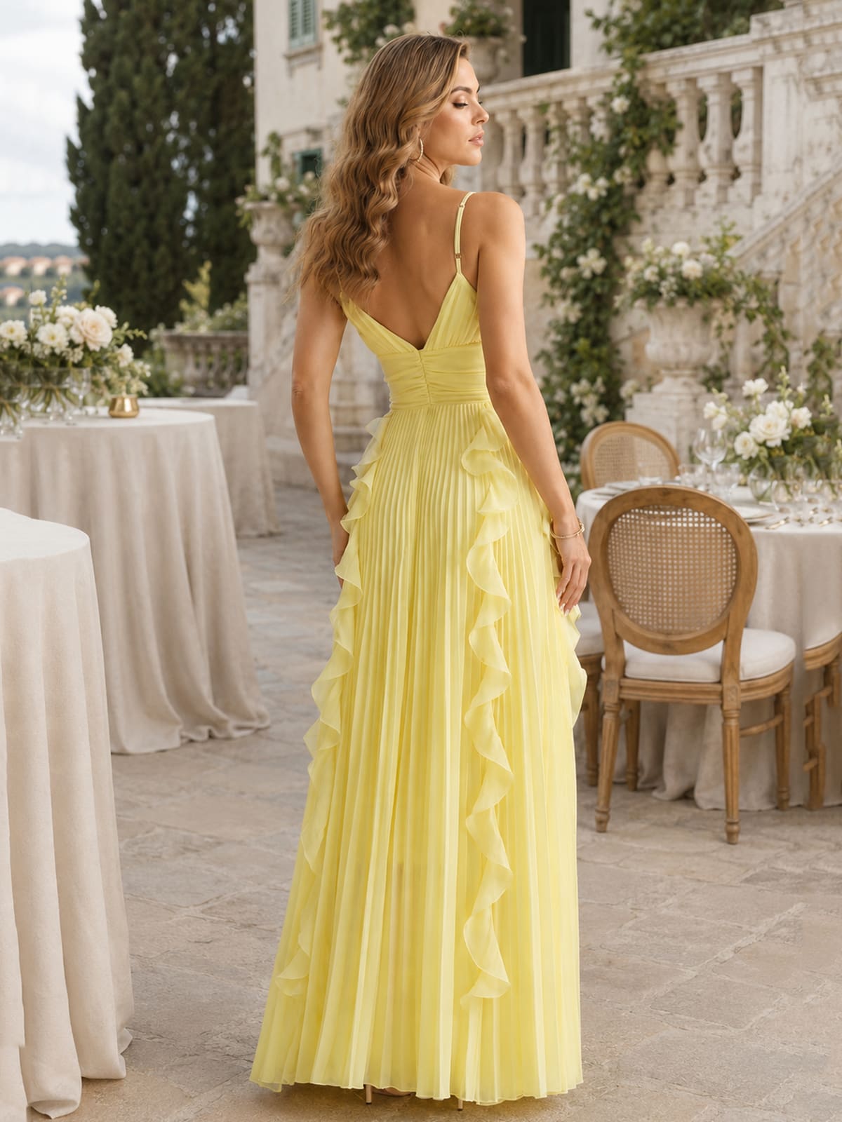 Back view of a yellow chiffon floor-length bridesmaid dress featuring slim spaghetti straps, a deep V-back neckline, wide ruched waistband, center-back closure, finely pleated A-line skirt, and cascading chiffon ruffle details flowing from the waist down the skirt.