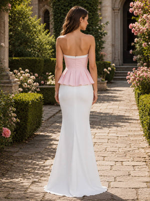 Back view of a colorblock satin floor-length bridesmaid dress featuring a straight strapless back, blush pink fitted bodice, structured peplum waist, concealed center-back zipper, and sleek white mermaid skirt with a softly flared hem.
