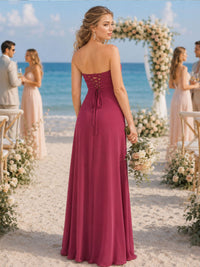 Back view of a fuchsia chiffon floor-length bridesmaid dress featuring a strapless fitted bodice, adjustable corset-inspired lace-up back with long tie ends, defined waist, and flowing A-line skirt.