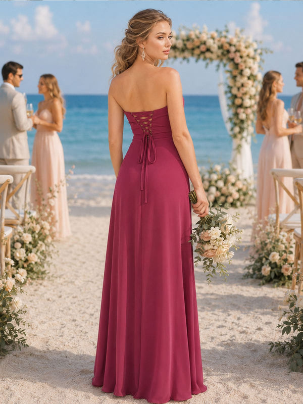 Back view of a fuchsia chiffon floor-length bridesmaid dress featuring a strapless fitted bodice, adjustable corset-inspired lace-up back with long tie ends, defined waist, and flowing A-line skirt.