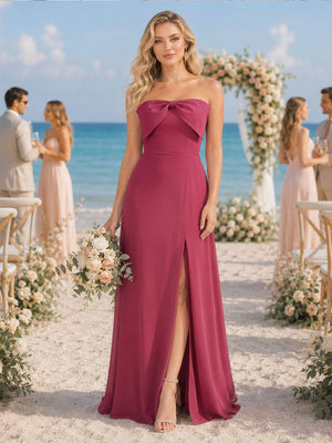 Front view of a fuchsia chiffon floor-length bridesmaid dress featuring a strapless neckline, oversized bow-front bodice detail, defined waist, flowing A-line silhouette, and elegant front thigh-high slit.