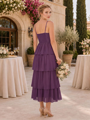 Back view of a plum chiffon tea-length bridesmaid dress featuring slim spaghetti straps, a smocked back bodice, fitted waist, and flowing layered tiered ruffle skirt.