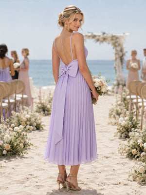 Back view of a lilac chiffon midi bridesmaid dress featuring slim spaghetti straps, a low open back, statement bow at the waist, finely pleated A-line skirt, and softly flowing midi hem.