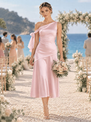 Front view of a light pink imitation silk bridesmaid dress featuring a one-shoulder neckline, ruched bodice, shoulder bow detail, elegant fit-and-flare silhouette, and tea-length hem.