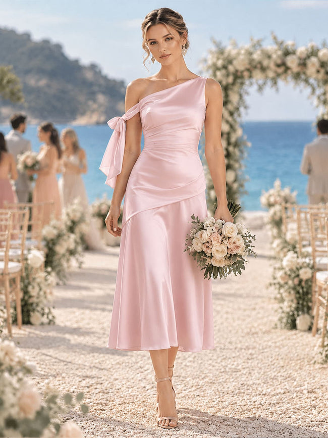 Front view of a light pink imitation silk bridesmaid dress featuring a one-shoulder neckline, ruched bodice, shoulder bow detail, elegant fit-and-flare silhouette, and tea-length hem.