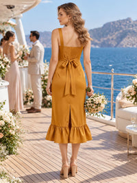 Back view of a golden ochre imitation silk bridesmaid dress featuring wide shoulder straps, a smocked back bodice, self-tie waist bow, fitted sheath silhouette, center-back slit, and ruffled tea-length hem.