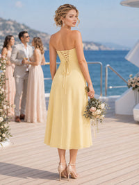 Back view of a daffodil chiffon bridesmaid dress featuring a strapless back, lace-up corset detail, fitted waist, softly flared A-line silhouette, and tea-length hem.