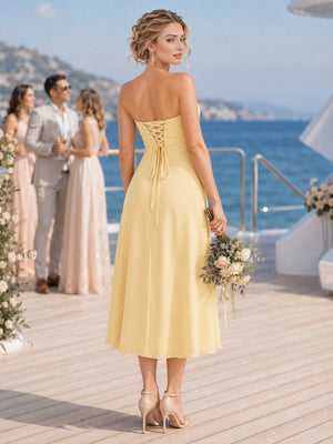 Back view of a daffodil chiffon bridesmaid dress featuring a strapless back, lace-up corset detail, fitted waist, softly flared A-line silhouette, and tea-length hem.