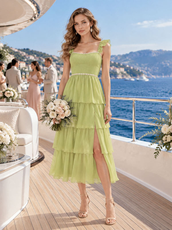 Front view of a pale lime chiffon bridesmaid dress featuring a square neckline, ruffle straps, ruched bodice, pearl trim, tiered A-line tea-length skirt, and a front slit.