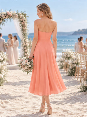 Back view of a soft apricot chiffon bridesmaid dress featuring a clean strapless back, fitted bodice, concealed center-back zipper, defined waist, and flowing tea-length A-line skirt.