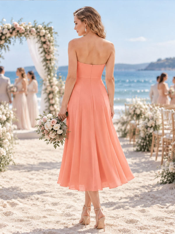 Back view of a soft apricot chiffon bridesmaid dress featuring a clean strapless back, fitted bodice, concealed center-back zipper, defined waist, and flowing tea-length A-line skirt.