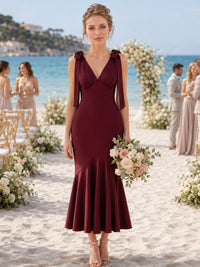 Front view of a burgundy imitation silk bridesmaid dress featuring a V-neckline, shoulder bow straps with ribbon tails, fitted bodice, elegant mermaid silhouette, and tea-length flared hem.