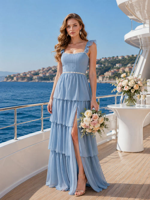 Front view of a light blue chiffon bridesmaid dress featuring a square neckline, ruffle straps, ruched bodice, defined waist trim, layered tiered floor-length skirt, and elegant side slit.