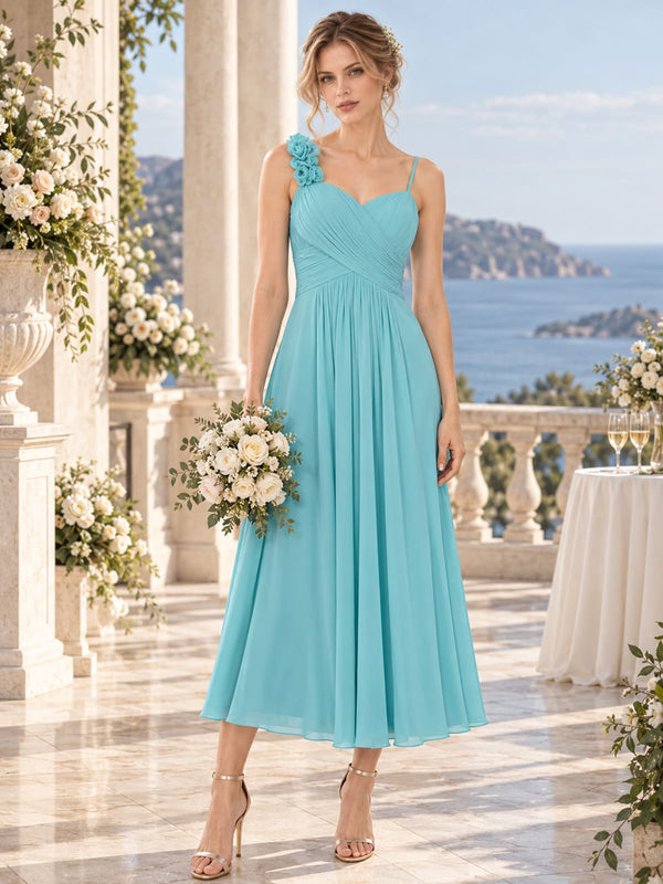 Aqua chiffon midi bridesmaid dress with spaghetti straps, floral shoulder detail and ruched bodice, front view.