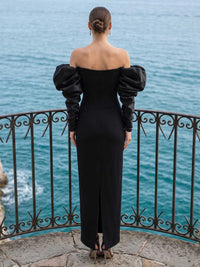Black satin fitted evening dress back view with off shoulder neckline, puff long sleeves, back slit, and concealed zipper