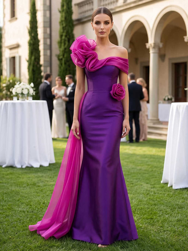 Satin mother of the bride dress front view with off-shoulder neckline, sculptural floral ruffle, waist flower accent, sheer side sash, fitted bodice, and floor length mermaid skirt