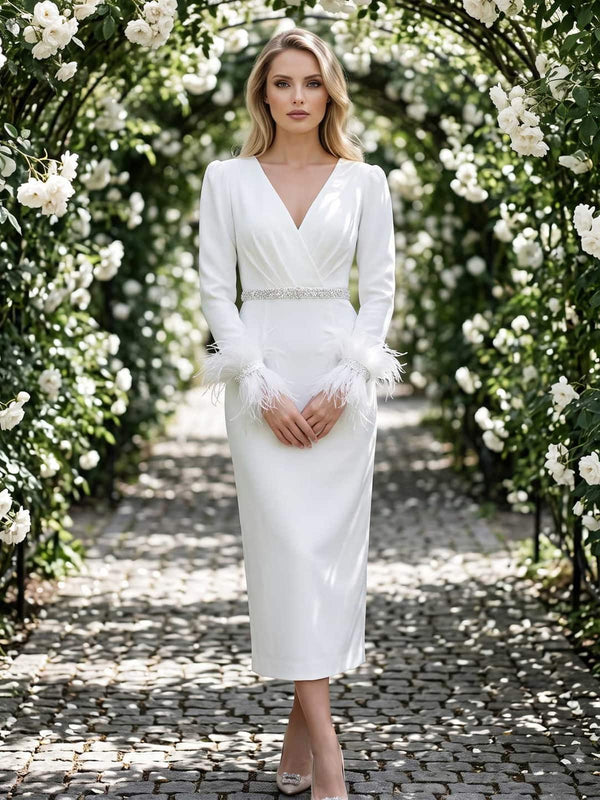 White satin mother of the bride dress front view with V-neckline, long sleeves, embellished waist detail, feather cuffs, fitted sheath silhouette, and tea length skirt