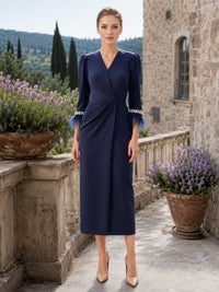 Navy blue satin mother of the bride dress front view with V neckline, tea length skirt, three quarter sleeves, pearl trim cuffs, and feather cuff details
