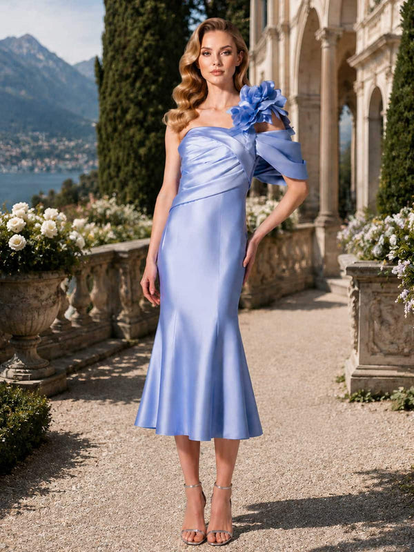 Periwinkle blue satin mother of the bride dress front view with one-shoulder neckline, ruched bodice, floral applique shoulder detail, fitted silhouette, and tea length mermaid skirt
