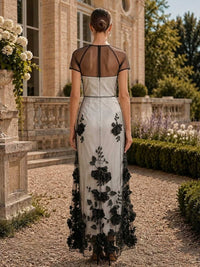 Floral tulle mother of the bride dress back view with sheer black illusion upper back, short sleeves, black floral lace overlay, concealed back zipper, and floor length skirt