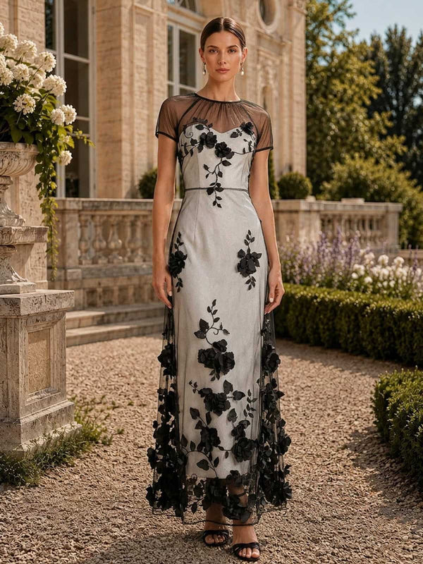 Floral tulle mother of the bride dress front view with illusion neckline, sheer short sleeves, black floral lace appliques, satin base, and floor length sheath skirt