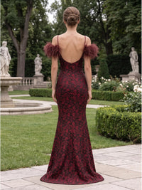 Back view of a burgundy and dark floral jacquard satin floor-length mother of the bride dress with low open back, delicate spaghetti straps, feather-trimmed off-the-shoulder detail, fitted mermaid silhouette, and center-back zipper.
