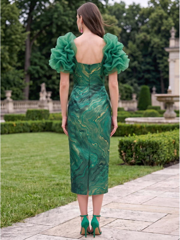 Back view of a jacquard satin midi mother of the bride dress with sculptural organza ruffle sleeves, square open back, fitted waist, center-back zipper, artistic green and gold jacquard pattern, and straight sheath skirt with back vent.