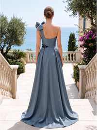 Back view of a slate blue satin floor-length mother of the bride dress with asymmetrical one-shoulder bow strap, softly shaped back neckline, black beaded waist embellishment, center-back zipper, and flowing A-line skirt.