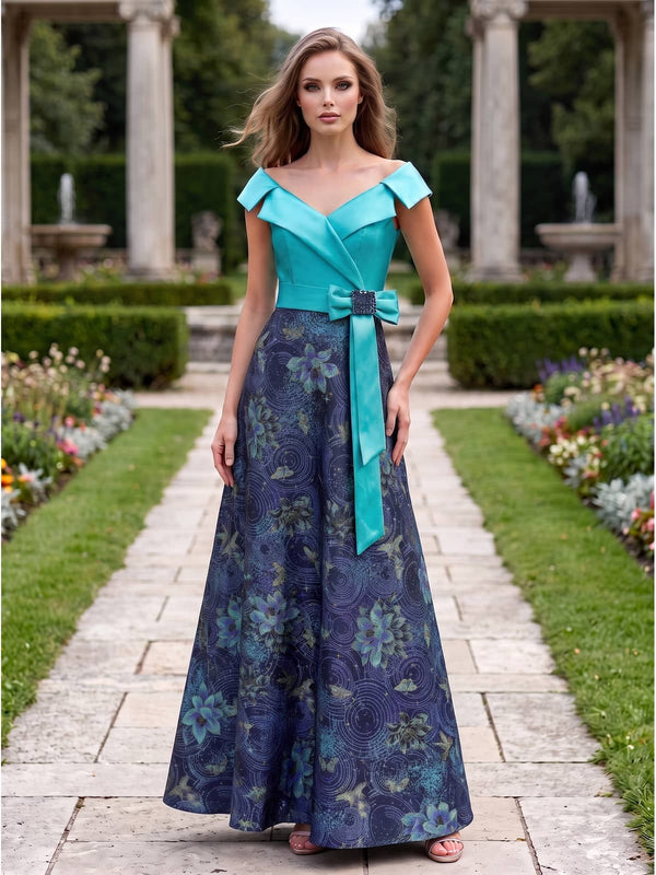 Front view of a mother of the bride dress featuring a turquoise satin off-the-shoulder bodice, matching waistband, decorative side bow with an embellished buckle, and a floor-length A-line jacquard satin skirt with a dark floral-inspired pattern.