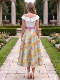 Back view of a floral jacquard satin tea-length mother of the bride dress with an off-the-shoulder fold-over neckline, center-back zipper, contrast pink waist sash, and full A-line skirt.