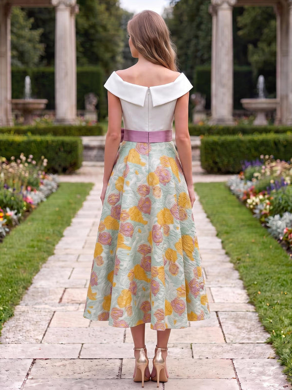 Back view of a floral jacquard satin tea-length mother of the bride dress with an off-the-shoulder fold-over neckline, center-back zipper, contrast pink waist sash, and full A-line skirt.
