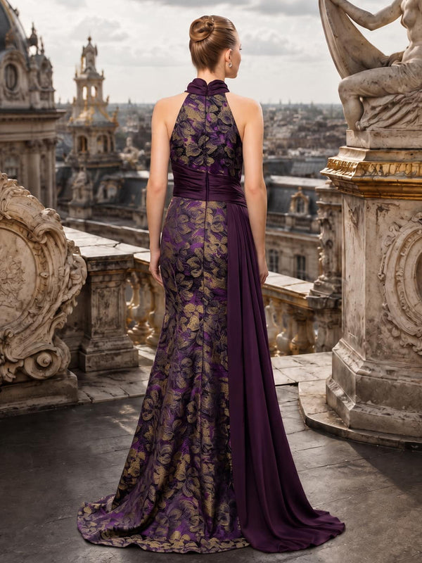 Back view of a floral jacquard satin floor-length mother of the bride gown with a high halter neckline, center-back zipper, fitted sheath silhouette, dark plum satin waist draping, and long coordinating side panel.