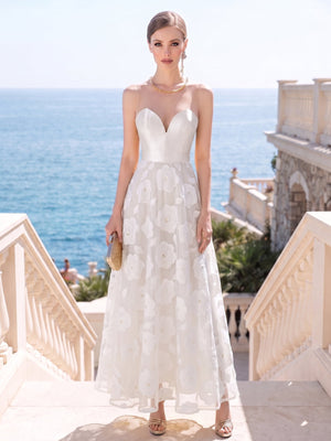 Front view of a floral lace tea-length mother of the bride dress featuring a structured sweetheart bodice, sheer illusion mesh neckline, sleeveless design, defined natural waist, dimensional floral lace A-line skirt, and an elegant refined silhouette.