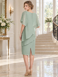 Back view of a sage green chiffon knee-length mother of the bride dress with short flutter sleeves, beaded shoulder detail, layered chiffon overlay, concealed center-back zipper, back slit, and sheath silhouette.