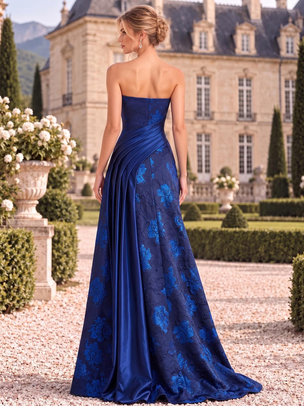 Back view of a floral jacquard satin mother of the bride dress featuring a clean strapless back, concealed center-back zipper, diagonal satin waist pleating, floral jacquard panels and a floor-length A-line silhouette.