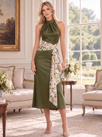 Front view of an elegant faux silk mother of the bride dress featuring a pleated halter neckline, sleeveless bodice, flattering A-line midi silhouette and contrasting embroidered floral sash wrapped around the waist with a long asymmetric draped detail.