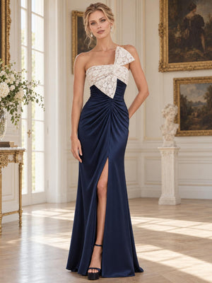 Front view of an elegant satin and floral lace mother of the bride dress featuring a fitted sheath silhouette, asymmetric neckline, contrasting floral lace bodice, statement shoulder bow, ruched waist and front slit.