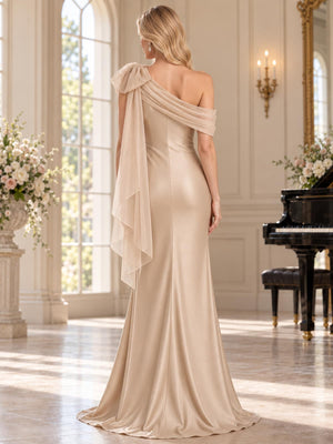Back view of an elegant faux silk mother of the bride dress featuring an asymmetric draped shoulder, statement organza bow with long cascading panels, fitted sheath silhouette, concealed center-back zipper and floor-length skirt.