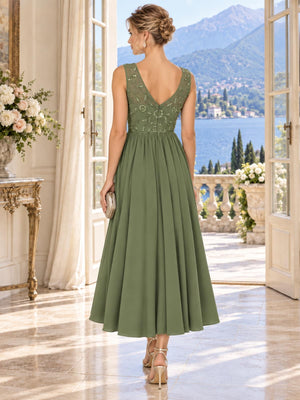 Back view of an elegant sage green chiffon mother of the bride dress featuring a deep V-back, coordinating floral beadwork and embellishments, defined waist and flowing tea-length A-line chiffon skirt.