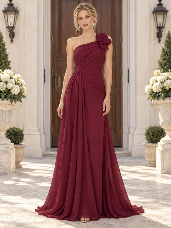 Front view of a burgundy chiffon mother of the bride dress featuring an asymmetric one-shoulder neckline, statement 3D floral shoulder embellishment, diagonally ruched bodice, draped waist and flowing floor-length A-line skirt.