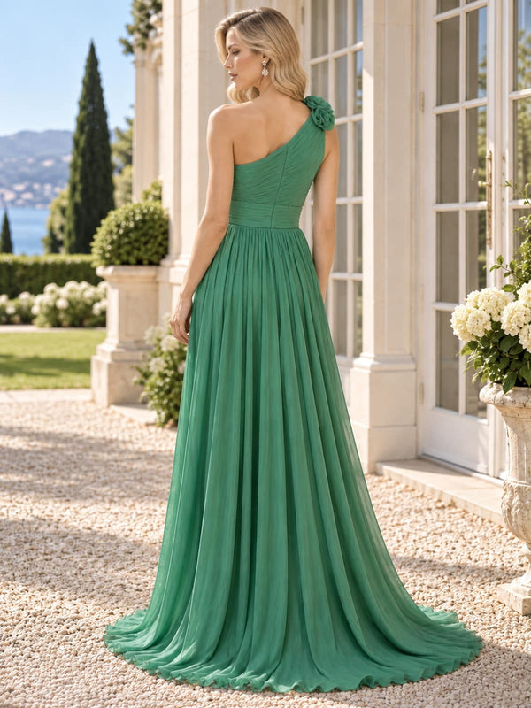 Back view of a green chiffon mother of the bride dress featuring an asymmetric one-shoulder design with dimensional floral appliqué, ruched bodice, defined waist, concealed back zipper and full flowing floor-length A-line chiffon skirt.