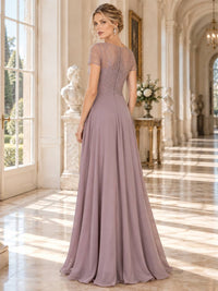 Back view of a floor-length lace and chiffon mother of the bride dress featuring a sheer embellished upper back, short sleeves, radiating bead and embroidery detailing, concealed center-back zipper and flowing A-line chiffon skirt.
