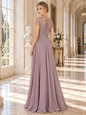 Back view of a floor-length lace and chiffon mother of the bride dress featuring a sheer embellished upper back, short sleeves, radiating bead and embroidery detailing, concealed center-back zipper and flowing A-line chiffon skirt.