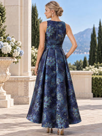 Back view of a navy floral jacquard satin mother of the bride dress featuring a sleeveless high neckline, fitted waist with coordinating belt and a structured A-line skirt with a longer back hem and all-over blue floral jacquard pattern.